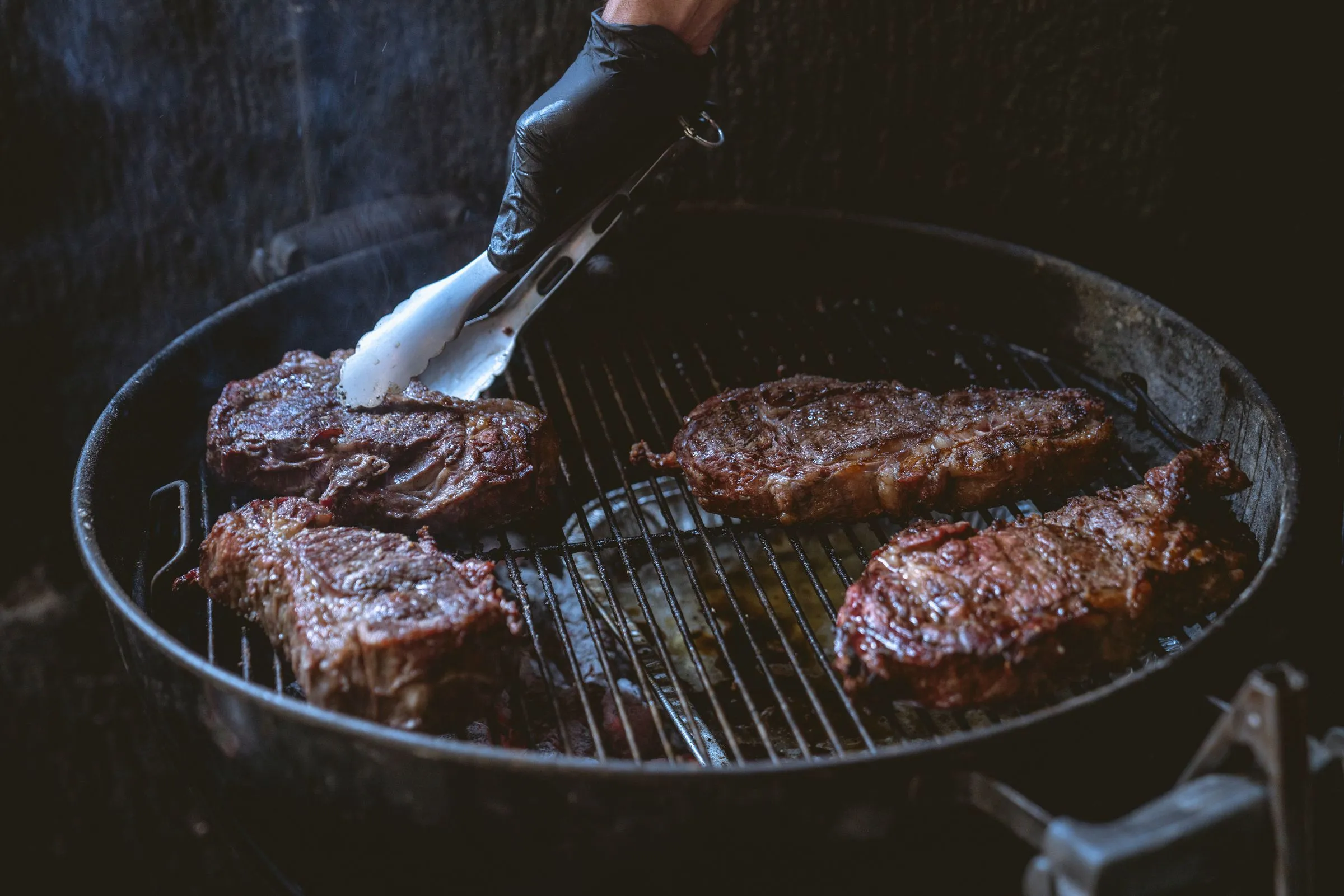 Piezas de carne asándose sobre parrilla redonda de carbón